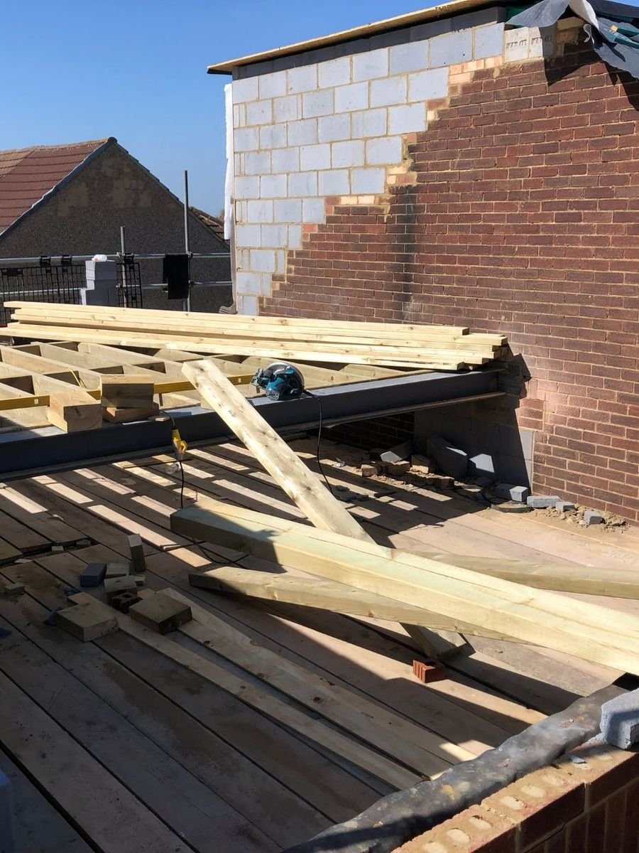 Extension de maison en chantier : poutre acier et chevrons de la future toiture