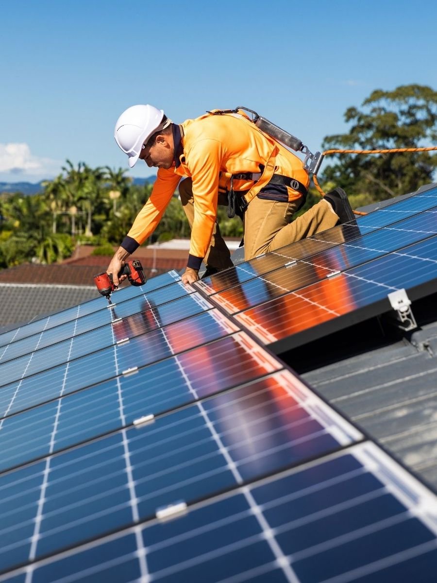 Installateur fixant des panneaux solaires sur le toit d'une maison